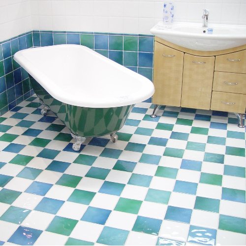 Bagno con vasca da bagno a piantana verde e pavimento a piastrelle bianche e verdi.