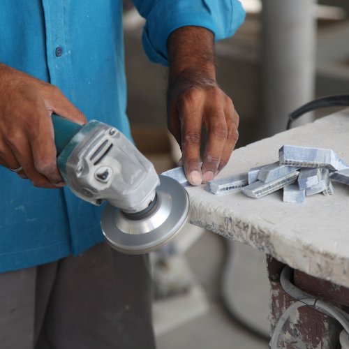Un marmista impegnato nella lavorazione artigianale di una lastra di marmo bianco.