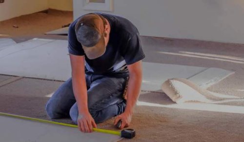 Un professionista durante la messa in posa della moquette in un appartamento.