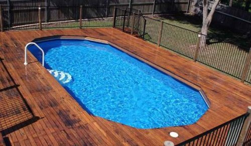Una piscina fuori terra con pedana in legno.