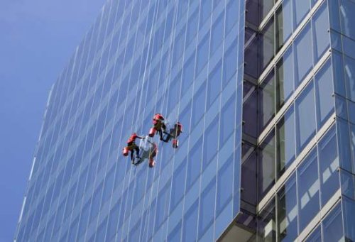 Pulizia della facciata di un edificio da parte di operatori su fune.