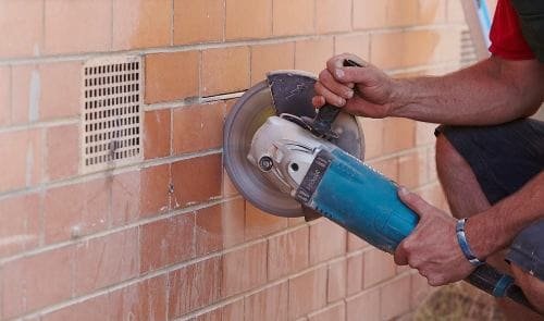 Esecuzione di un taglio a forza di muratura con disco diamantato.