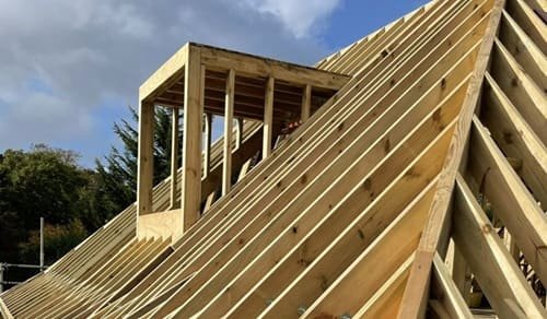 Tetto a padiglione con struttura in legno e abbaino in corso di costruzione.