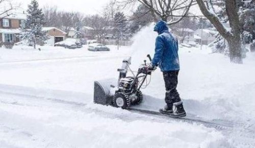 Sgombero della neve in un cortile con l'uso di una minipala.