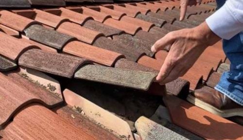 Rimozione delle tegole rotte di un tetto.